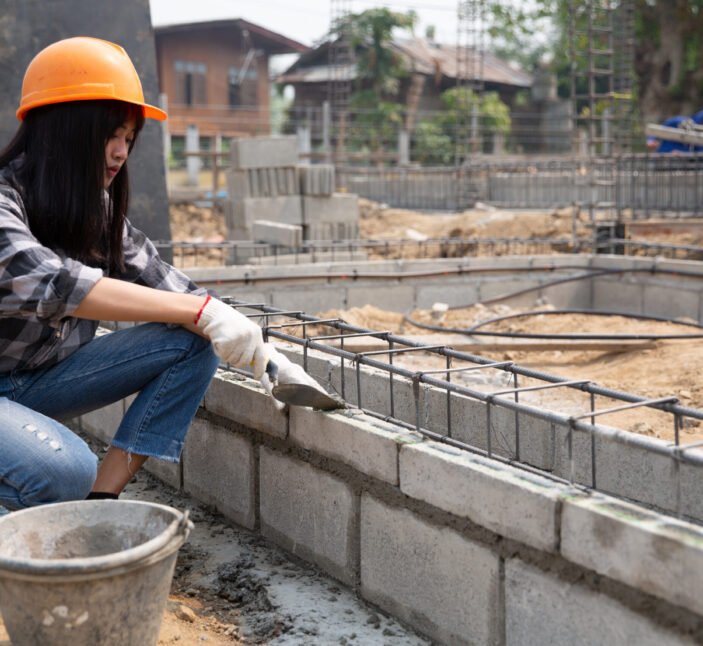 Bricklayer worker installing brick masonry on exterior wall with trowel putty knife