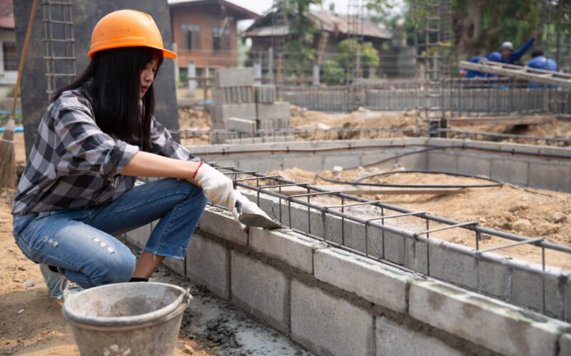 Bricklayer worker installing brick masonry on exterior wall with trowel putty knife